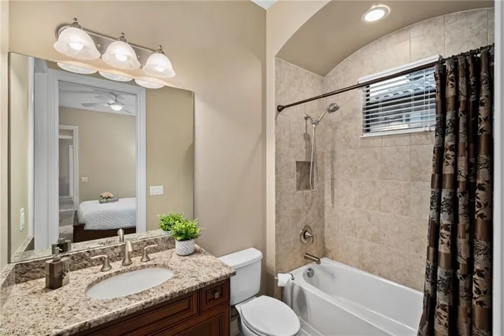 Full bathroom featuring shower / bath combo with shower curtain, vanity, ceiling fan, and toilet