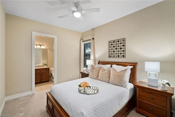 Bedroom featuring light carpet, ensuite bath, ceiling fan, and sink
