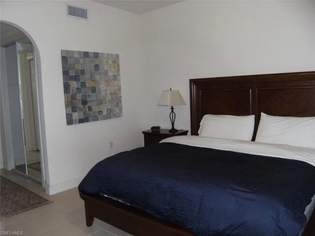Bedroom featuring arched walkways and light tile patterned floors