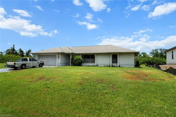 Ranch-style house featuring an attached garage, concrete driveway, and a front yard