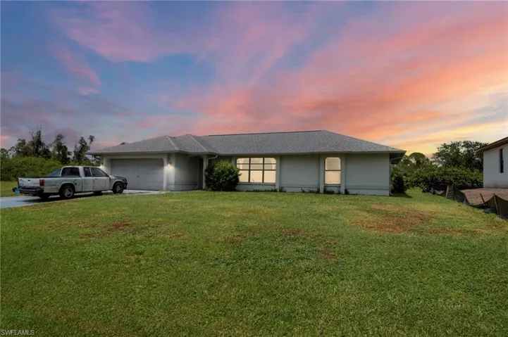 View of front of property with a garage, a lawn, and driveway