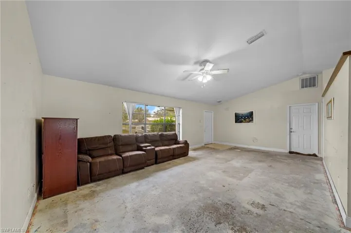 Living area with lofted ceiling, a ceiling fan, and concrete flooring