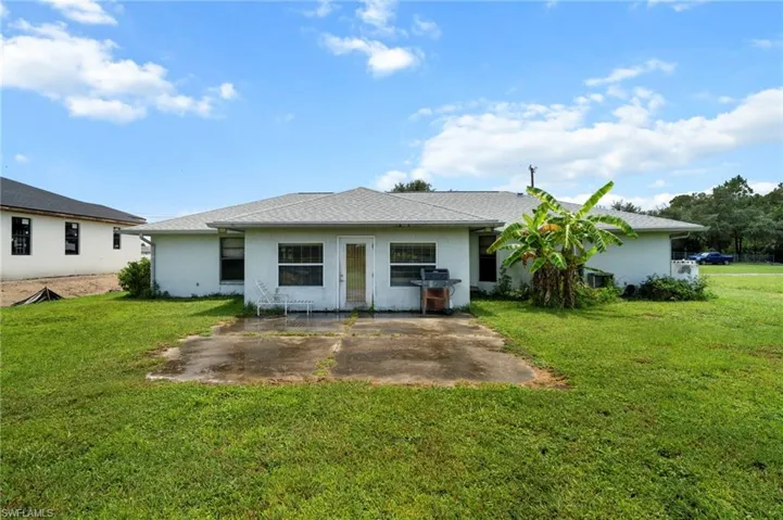 Rear view of house featuring a patio area, stucco siding, and a lawn