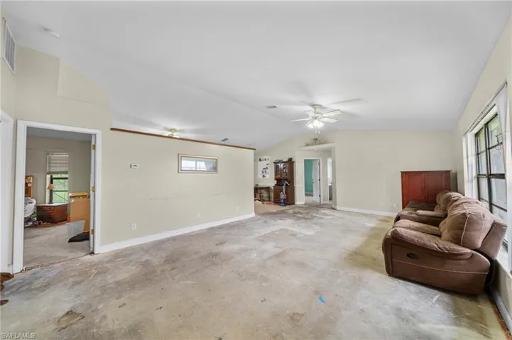 Living room featuring plenty of natural light, lofted ceiling, unfinished concrete flooring, and ceiling fan