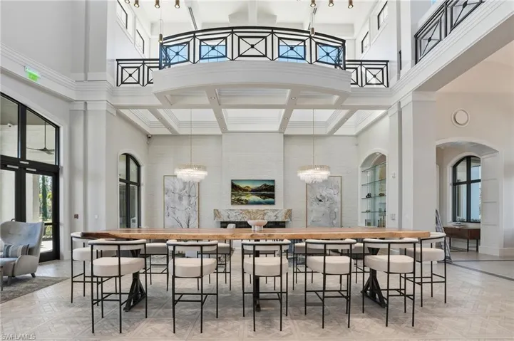 Bar area featuring plenty of natural light, a towering ceiling, decorative light fixtures, and beamed ceiling