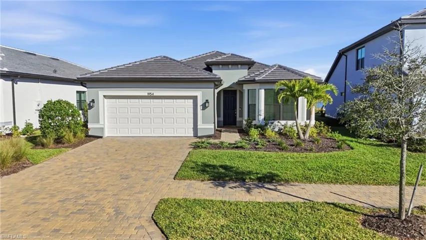 View of front of house with stucco siding, decorative driveway, and a front yard