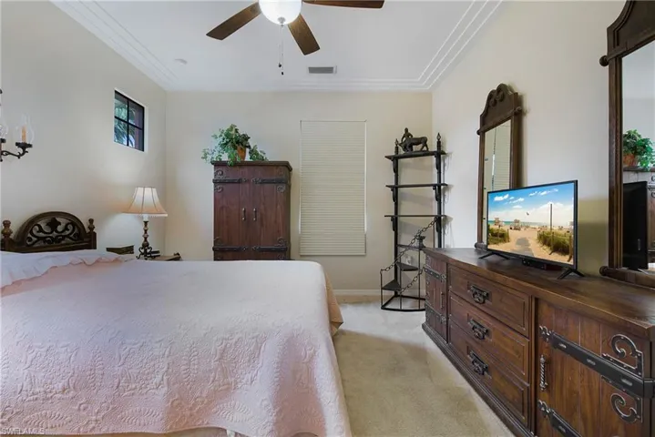 Bedroom with light colored carpet, baseboards, ceiling fan, and crown molding