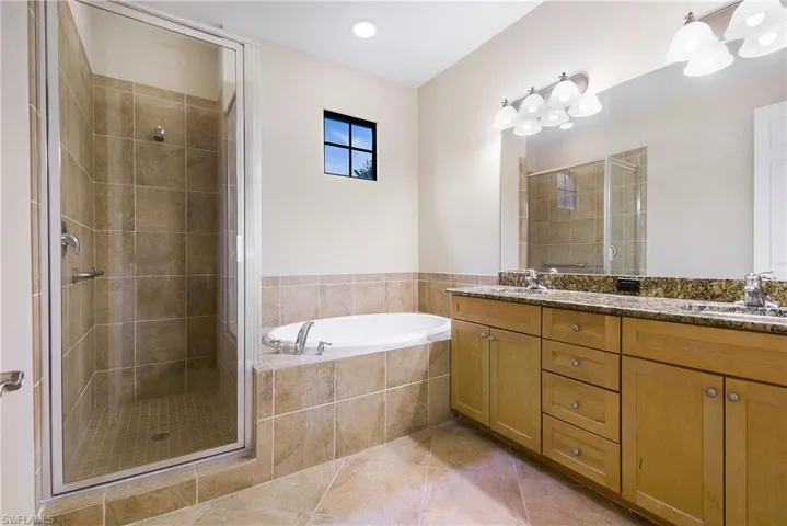 Full bathroom featuring a shower stall, double vanity, a garden tub, and tile patterned flooring