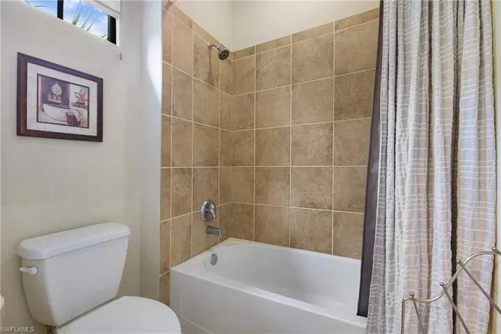 Bathroom featuring toilet and shower / tub combo with curtain