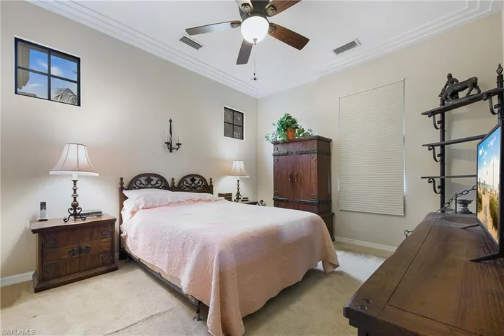 Bedroom featuring light carpet, baseboards, ornamental molding, and a ceiling fan