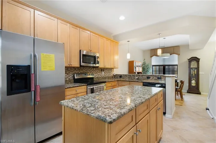 Kitchen featuring appliances with stainless steel finishes, a sink, a peninsula, stone countertops, and tasteful backsplash
