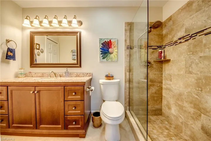 Bathroom featuring tiled shower, vanity, toilet, and tile patterned floors