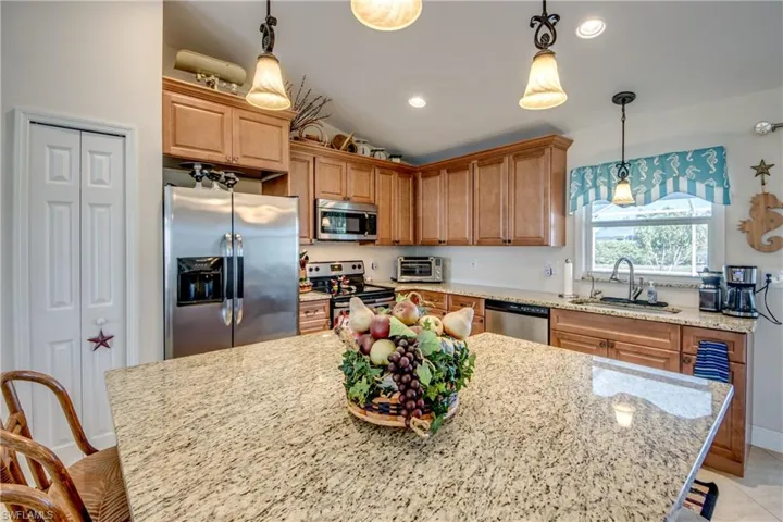 Kitchen featuring stainless steel appliances, a kitchen island, sink, and hanging light fixtures