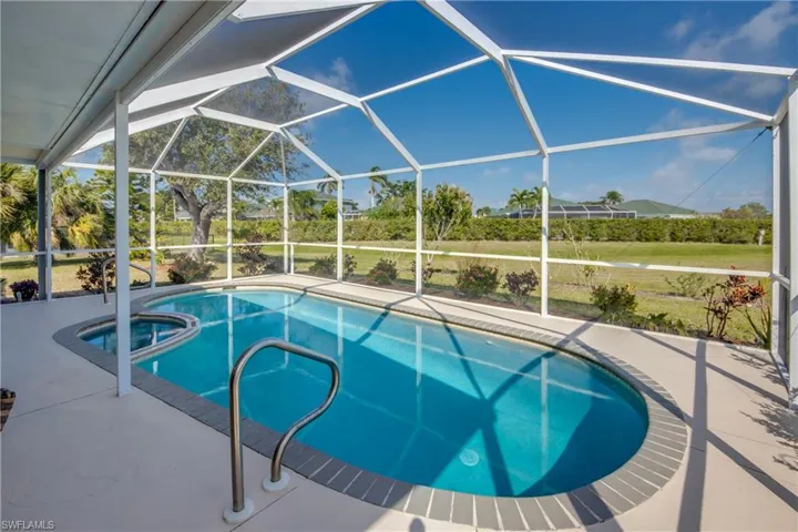 View of swimming pool featuring an in ground hot tub, glass enclosure, and a patio area