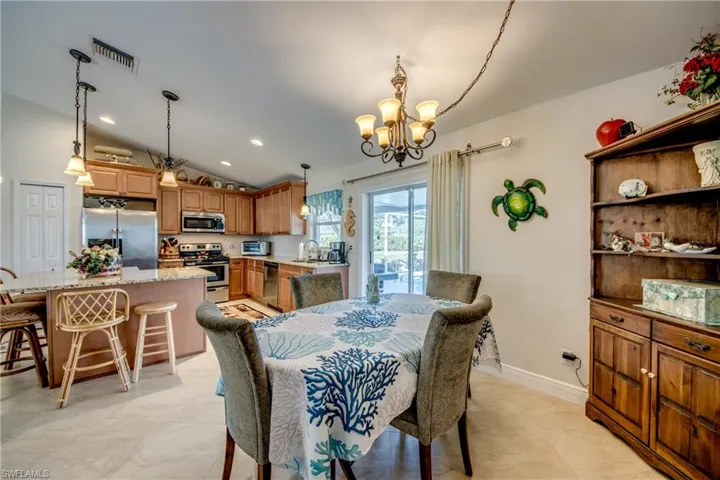 Dining area featuring sink, vaulted ceiling, and a notable chandelier