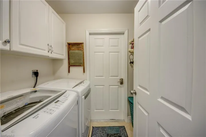 Washroom featuring cabinets, light tile patterned floors, and washer and clothes dryer