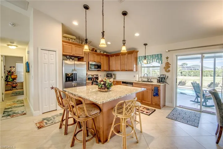 Kitchen featuring lofted ceiling, sink, a center island, light tile patterned floors, and stainless steel appliances