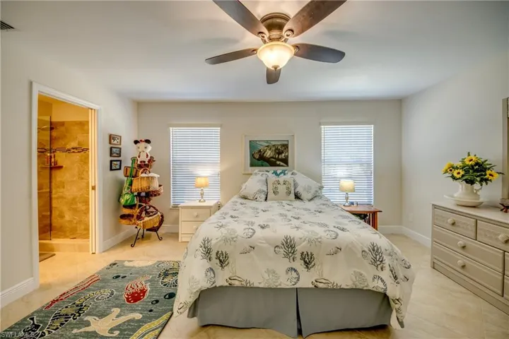 Tiled bedroom featuring connected bathroom and ceiling fan