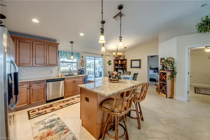 Kitchen featuring a kitchen island, appliances with stainless steel finishes, sink, a breakfast bar area, and light stone countertops