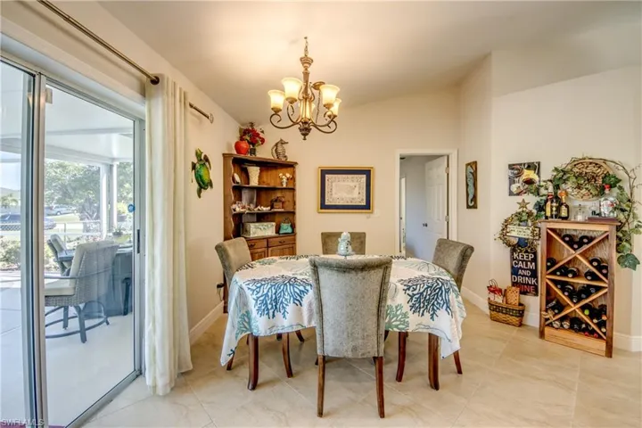 Dining area with lofted ceiling, light tile patterned floors, and a notable chandelier