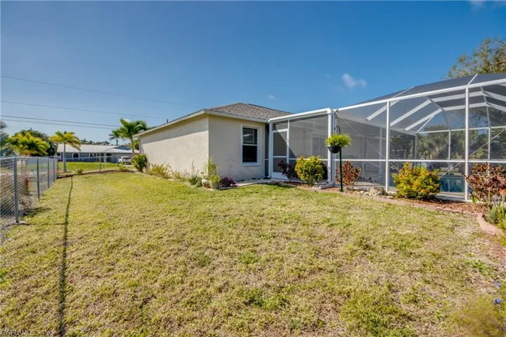 Back of property with glass enclosure and a lawn
