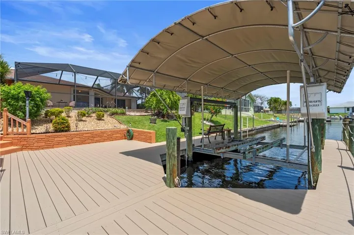 Dock featuring boat lift and a water view  Photo virtually enhanced.