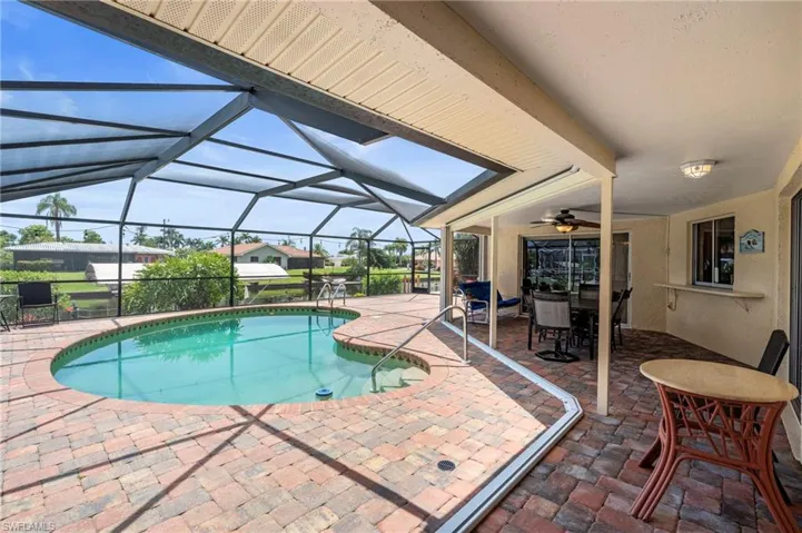 Swimming pool featuring a patio, a ceiling fan, outdoor dining space, and a lanai  Photo virtually enhanced.