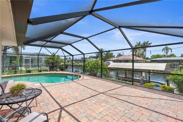 Outdoor pool with a patio area, a water view,