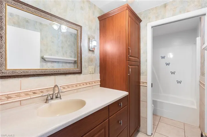 Bathroom with vanity, tile patterned floors, and bathtub / shower combination