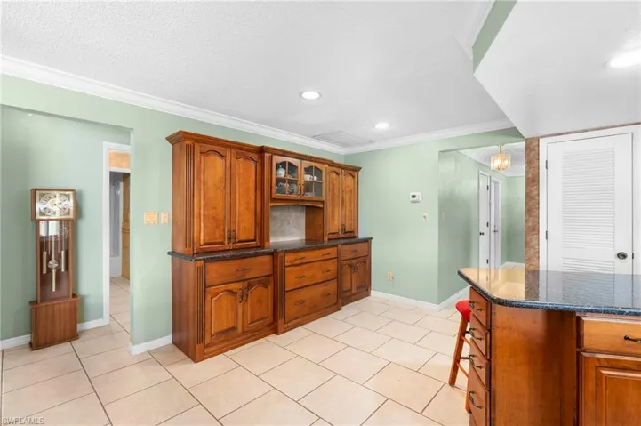 Kitchen with light tile patterned flooring, brown cabinets, glass insert cabinets, recessed lighting, and baseboards