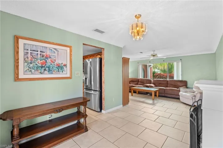 Living area with a ceiling fan, light tile patterned floors, a chandelier, and baseboards