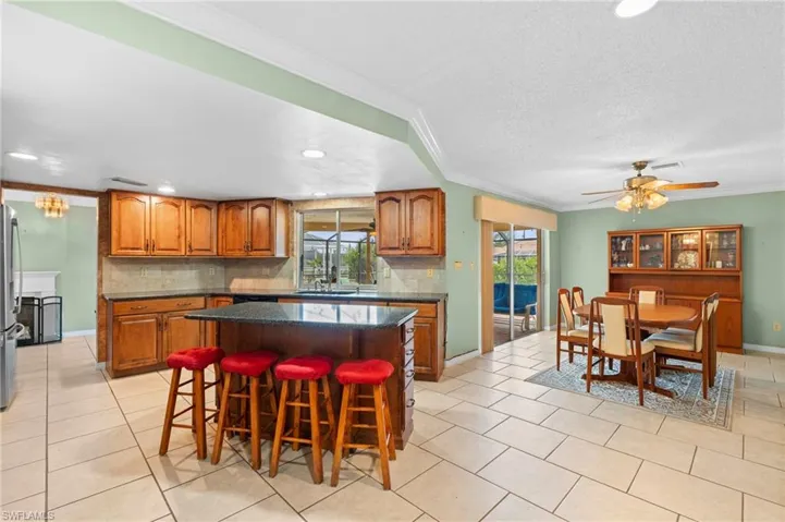 Kitchen with brown cabinetry, ornamental molding, backsplash, a sink, and a center island