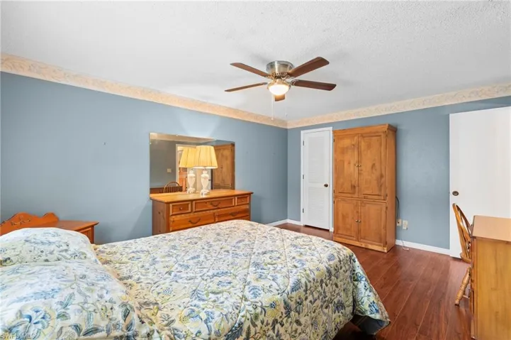 Bedroom featuring dark wood-type flooring, baseboards, a ceiling fan, and a textured ceiling