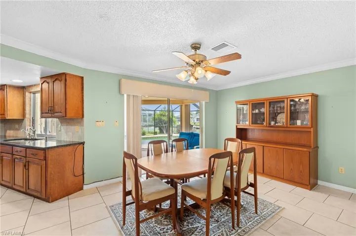 Dining space with a ceiling fan, crown molding, light tile patterned floors, a textured ceiling, and baseboards