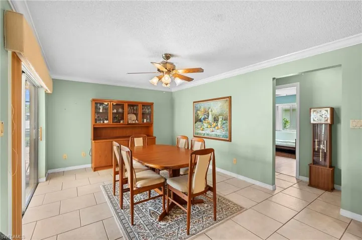 Dining space with plenty of natural light, a textured ceiling, ornamental molding, ceiling fan, and light tile patterned floors