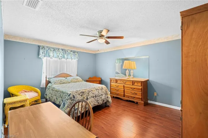 Bedroom featuring a textured ceiling, wood finished floors, baseboards, and a ceiling fan