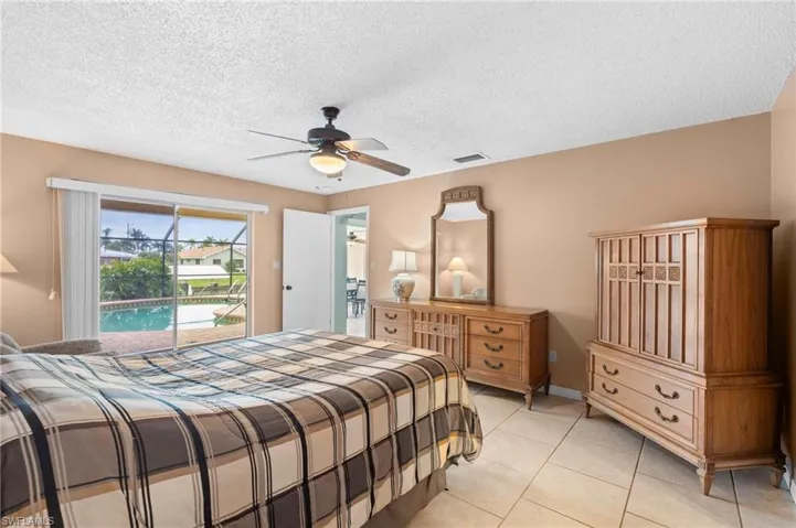 Bedroom with access to outside, light tile patterned floors, ceiling fan, and a textured ceiling