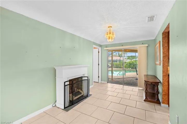 Unfurnished living room with baseboards, a fireplace, a chandelier, light tile patterned flooring, and a textured ceiling