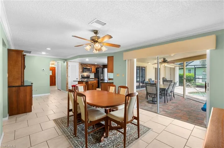 Dining space with a ceiling fan, crown molding, light tile patterned floors, a textured ceiling, and baseboards