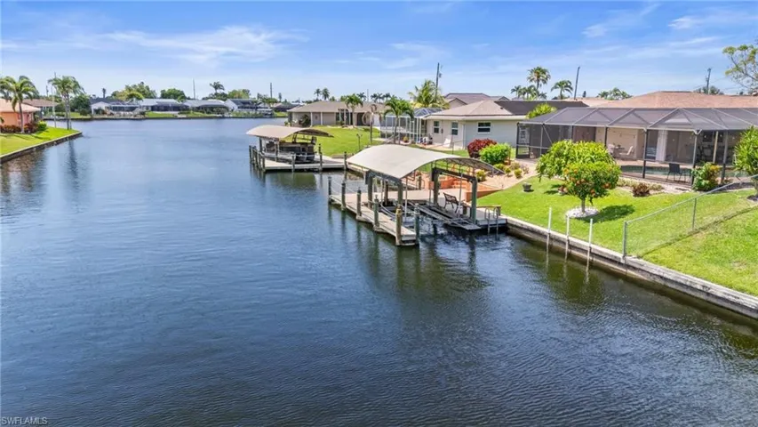 Dock with boat lift, a residential view, and a water view  Photo virtually enhanced.