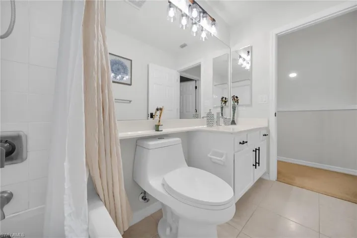 Bathroom with shower / bath combination with curtain, light tile patterned flooring, and vanity