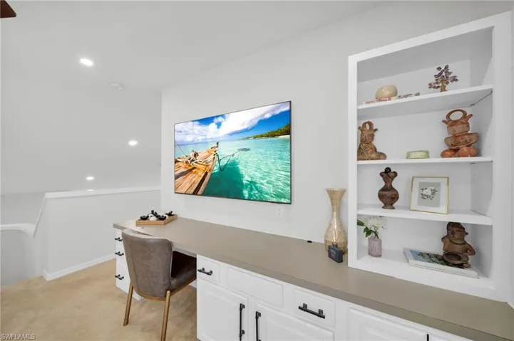Office space featuring light colored carpet, recessed lighting, and built in shelves