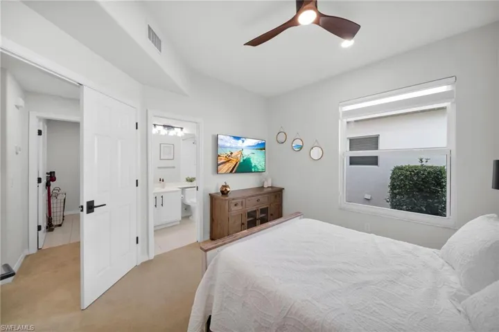 Bedroom featuring light carpet, a ceiling fan, and ensuite bath