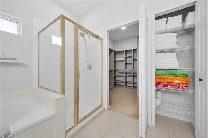 Full bath featuring a walk in closet, a shower stall, a bath, and light tile patterned floors