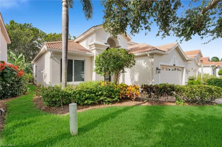 View of front of house featuring a front yard, stucco siding, a tile roof, and an attached garage