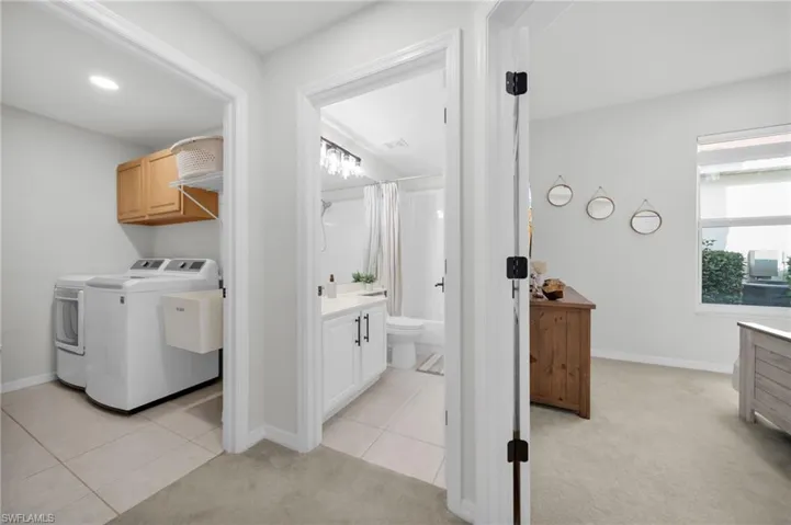 Laundry area with light colored carpet, light tile patterned flooring, washer and clothes dryer, and recessed lighting