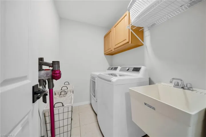 Laundry room featuring independent washer and dryer, cabinet space, and light tile patterned floors