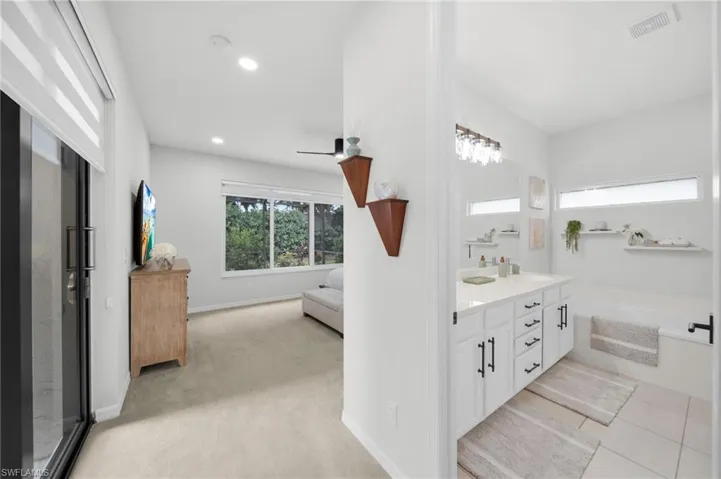Bathroom with double vanity, ensuite bath, and light colored carpet