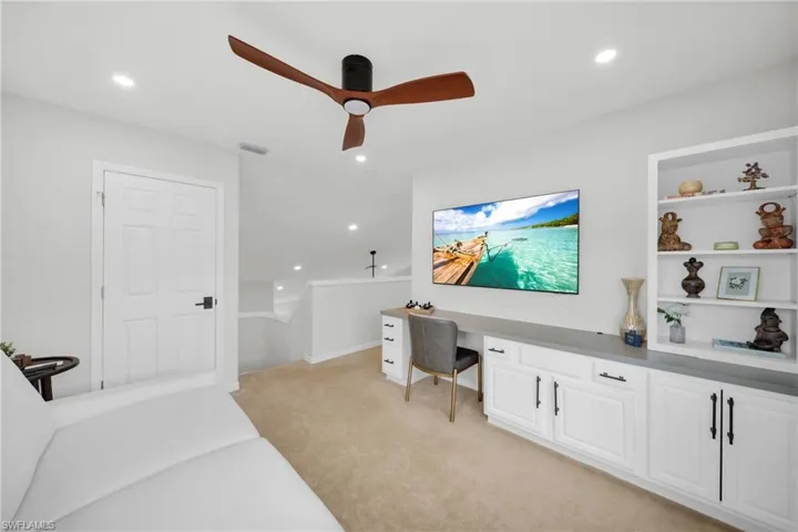 Bedroom featuring light colored carpet, a ceiling fan, recessed lighting, and built in desk