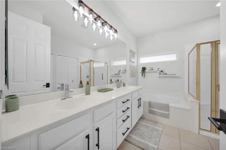 Bathroom with a shower stall, double vanity, a bath, light tile patterned floors, and recessed lighting
